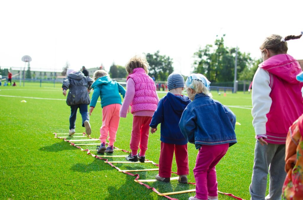 pexels photo 296301 296301 Children enjoy an outdoor activity on a grassy field, stepping over a ladder.